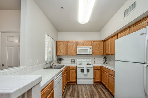 Wood plank floors with refrigerator dishwasher self-cleaning range and over the range microwave and kitchen window